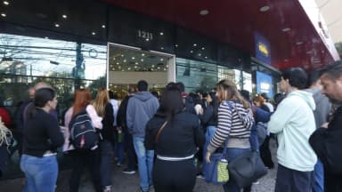 Candidatos aguardam em fila na entrada de um local de prova de concurso público