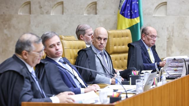 Ministros do Supremo Tribunal Federal, de toga, sentados à bancada durante sessão plenária, com a bandeira do Brasil ao fundo, em imagem de arquivo de abril de 2026