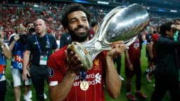 Mohamed Salah segura troféu em campo com camisa vermelha do Liverpool