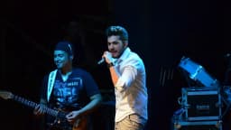 Gustavo Mioto canta ao microfone em show, com banda ao fundo (foto de arquivo)