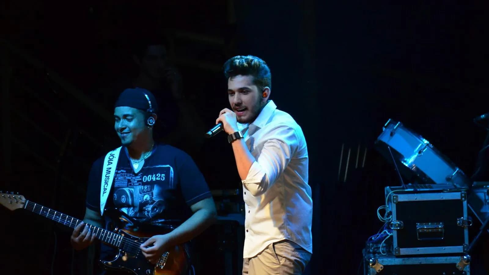 Gustavo Mioto canta ao microfone em show, com banda ao fundo (foto de arquivo)