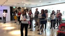 Fila de brasileiros em posto de votação no exterior, com famílias aguardando para votar