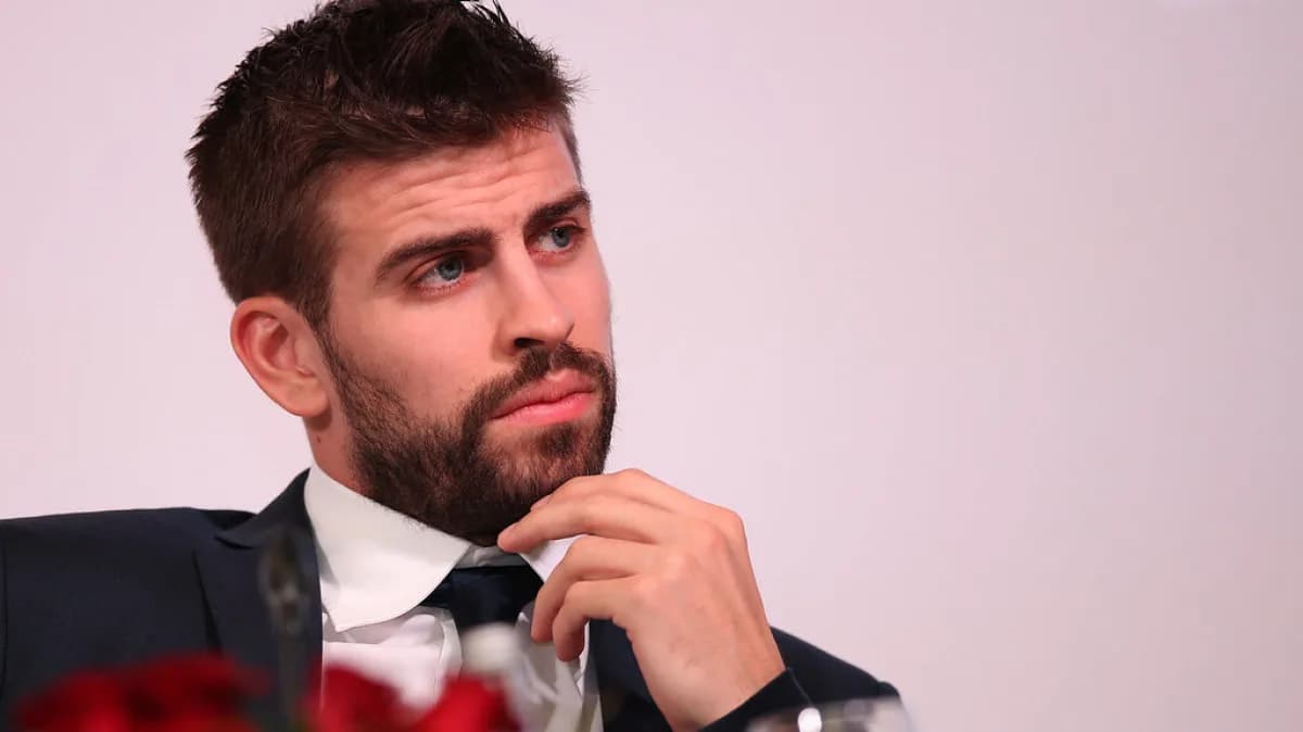 Gerard Piqué fala ao microfone em evento, vestindo terno