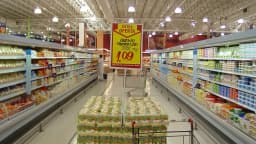 Corredor de supermercado com prateleiras de produtos e carrinho de compras