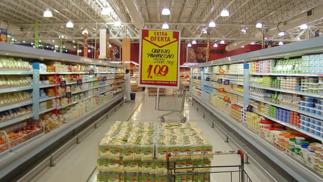 Corredor de supermercado com prateleiras de produtos e carrinho de compras
