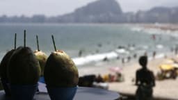 Águas de coco à venda em Copacabana, com a praia cheia ao fundo