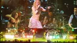 Shakira se apresenta no palco com dançarinos ao fundo