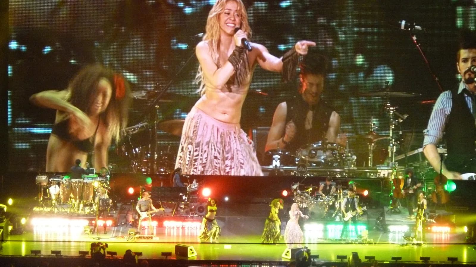 Shakira se apresenta no palco com dançarinos ao fundo