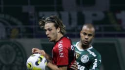 Jogador do Athletico Paranaense, de vermelho e preto, disputa bola com adversário do Palmeiras durante partida