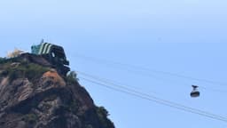Bondinho do Pão de Açúcar em movimento sobre os cabos, com a estação no alto do morro ao fundo, no Rio de Janeiro