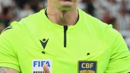 O árbitro Anderson Daronco, de uniforme verde, gesticula durante partida de futebol