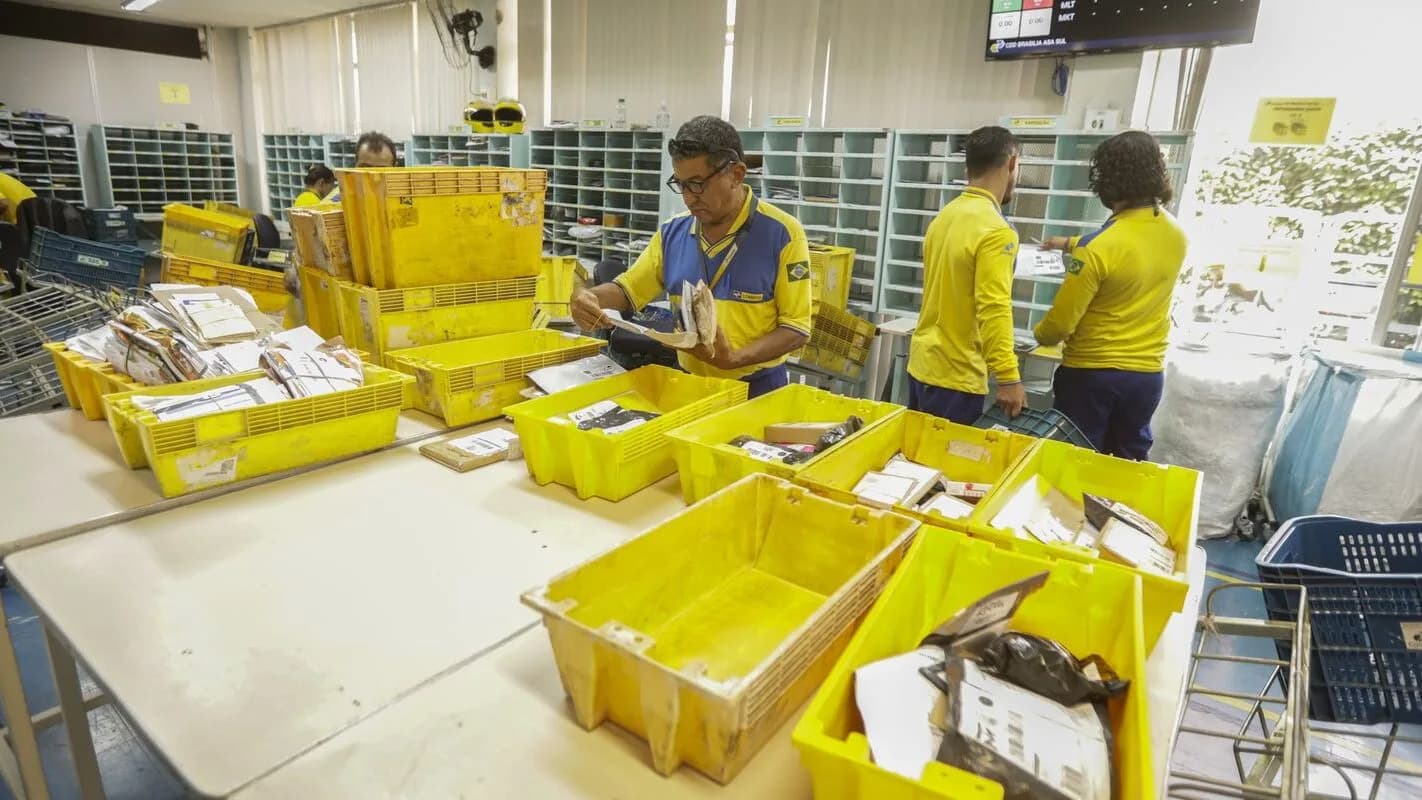 Funcionários dos Correios triam caixas amarelas de encomendas de comércio eletrônico internacional