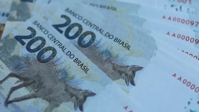 Notas de reais do Banco Central do Brasil espalhadas, com destaque para a nota de R$ 200