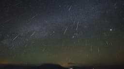 Céu noturno estrelado com rastros de meteoros visíveis, imagem ilustrativa de chuva de meteoros