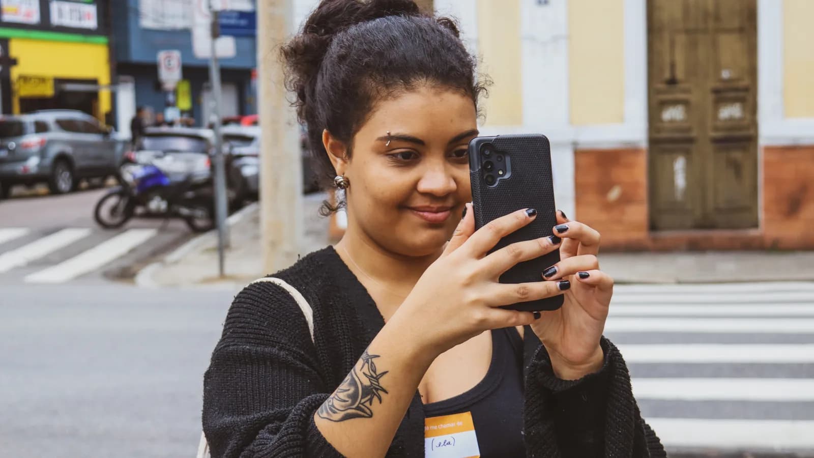 Jovem usa celular caminhando por rua da cidade