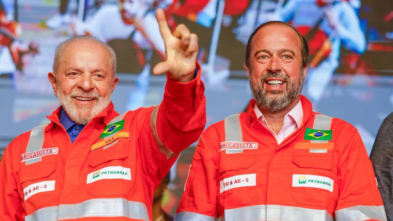 Lula e o ministro Alexandre Silveira sorriem em cerimônia em fábrica de fertilizantes, vestindo macacão vermelho de brigadista com o logo da Petrobras