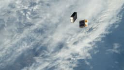 Pequenos satélites são liberados no espaço com a Terra e nuvens ao fundo, vistos a partir da Estação Espacial Internacional