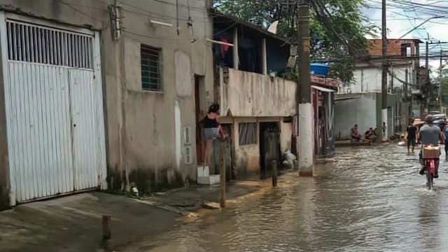 Moradores atravessam rua alagada em São Paulo