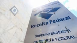 Placa externa da Superintendência da Receita Federal, com o logotipo do órgão e a inscrição Ministério da Fazenda, ao lado da fachada do prédio; imagem de arquivo