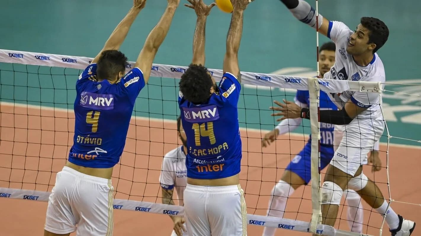Jogadores disputam bola no bloqueio durante partida de vôlei masculino