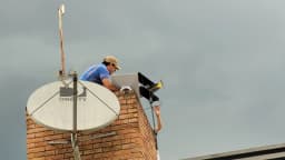 Homem instala antena e terminal de usuário do Starlink em telhado