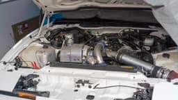 Cofre de motor aberto de um Pontiac Firebird Turbo Trans Am 1989 modificado, com dutos de admissão de alumínio e filtro de ar cônico à direita