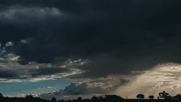 Céu tomado por nuvens escuras de tempestade ao entardecer, com feixes de luz entre as nuvens