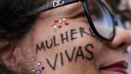 Rosto de mulher com a frase mulher viva escrita no rosto, em protesto contra a violência de gênero