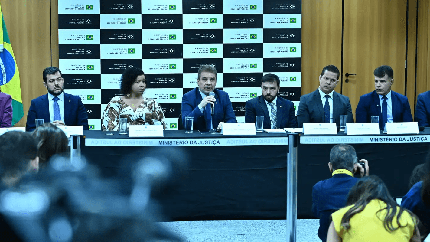Ministro da Justiça e Segurança Pública fala ao microfone em coletiva de imprensa sobre operação contra rede que aliciava adolescentes na internet, ao lado de outras autoridades, em Brasília