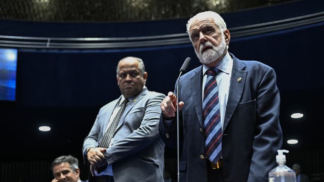 O senador Jaques Wagner discursa em pé, diante do microfone, durante sessão no plenário do Senado; ao lado, outros dois senadores acompanham a fala. Imagem de arquivo.