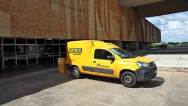 Van amarela dos Correios com identificação Sedex estacionada em frente a prédio público em Brasília