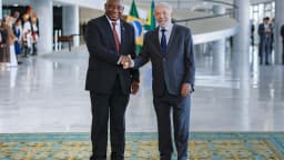 Lula sorri ao lado do presidente da África do Sul, Cyril Ramaphosa, em cumprimento no Palácio do Planalto