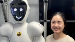 Engenheira sorri ao lado de robô humanoide branco com rosto digital, imagem ilustrativa de robô humanoide colaborativo