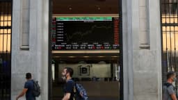 Pessoas passam em frente ao painel eletrônico da B3, bolsa de valores brasileira, em São Paulo