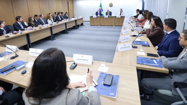 Ministro Alexandre de Moraes participa de reunião institucional em mesa com bandeira do Brasil ao fundo