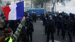 Manifestante segura bandeira da França em frente a policiais durante protesto em Paris