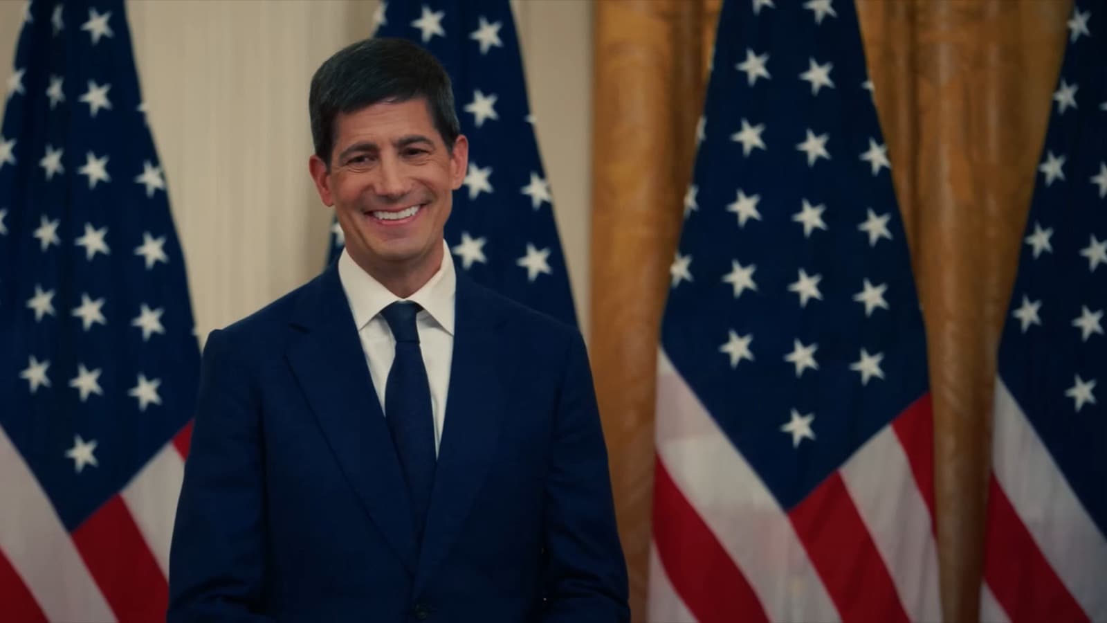 Foto de arquivo do presidente do Federal Reserve, Kevin Warsh, de terno azul-escuro e gravata, sorrindo diante de bandeiras dos Estados Unidos durante sua posse na Casa Branca, em maio de 2026
