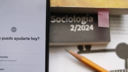 Tela de celular com o aplicativo do ChatGPT aberto ao lado de caderno e lápis