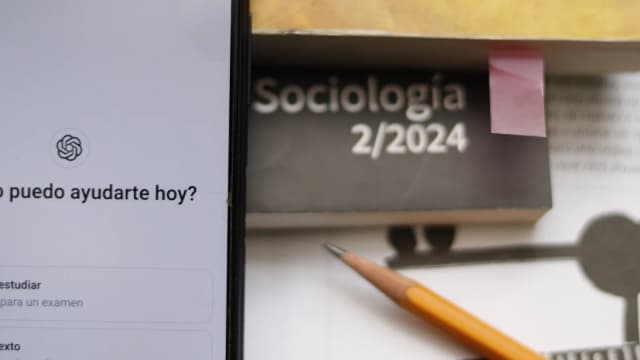 Tela de celular com o aplicativo do ChatGPT aberto ao lado de caderno e lápis