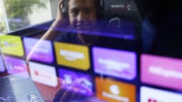 Pessoa assiste a conteúdo em tela com ícones de aplicativos de streaming e redes sociais