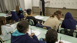 Professora dá aula para turma de alunos em sala de aula do ensino fundamental