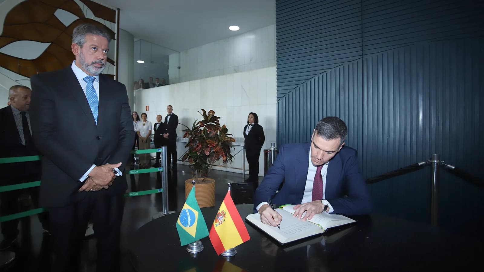 Pedro Sánchez assina documento em mesa com bandeiras do Brasil e da Espanha, durante visita oficial