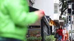 Pessoas caminham agasalhadas em calçada de São Paulo durante frente fria