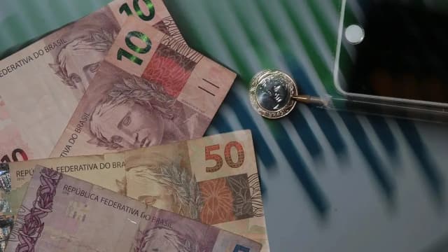Cédulas e moedas de real sobre mesa, foto de arquivo sobre a economia brasileira