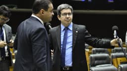 Dois deputados conversam em frente aos microfones no plenário do Congresso