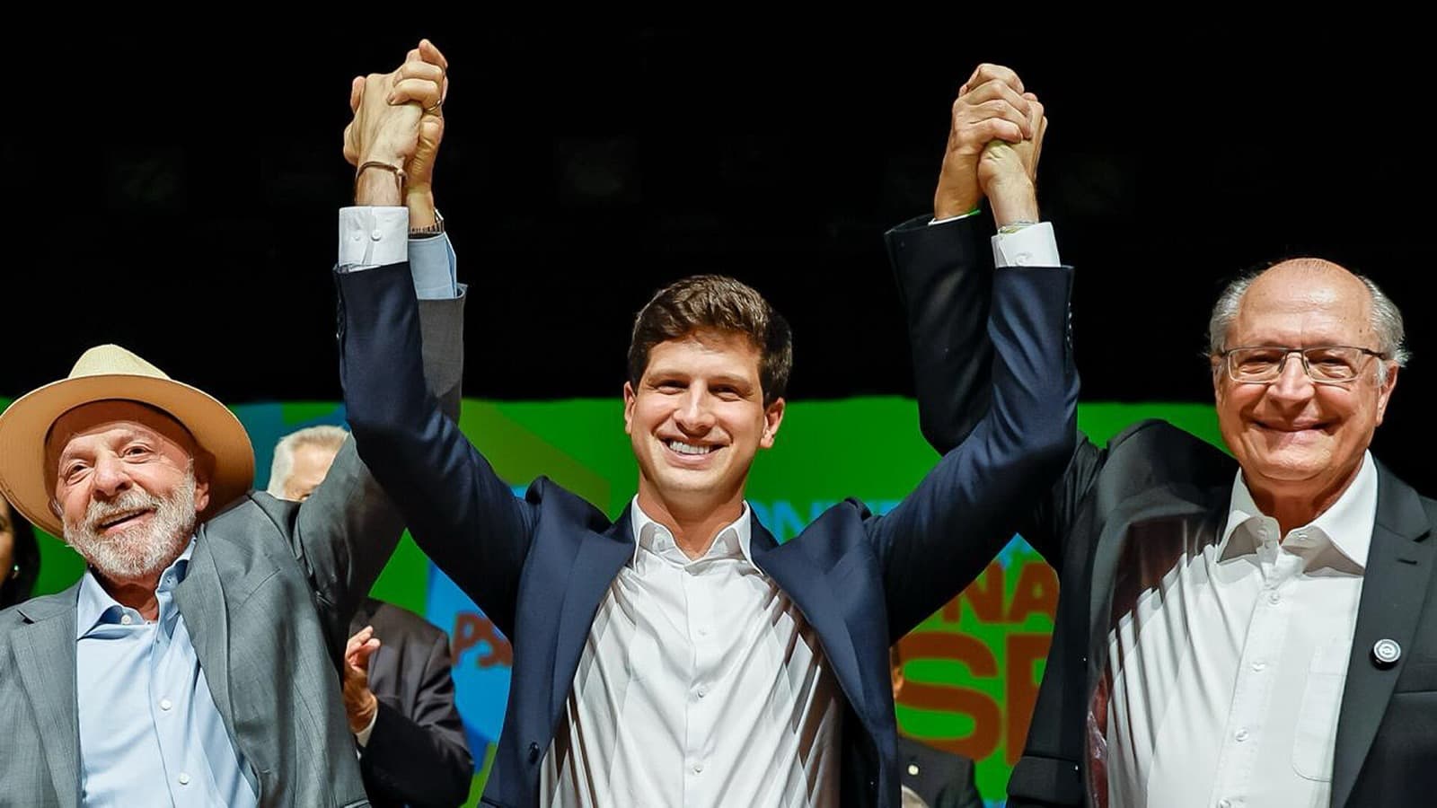 Lula, de chapéu de palha, e Geraldo Alckmin, à direita, erguem as mãos ao lado de João Campos durante a convenção nacional do PSB, em 29 de julho de 2026; imagem de arquivo
