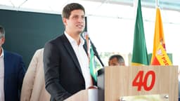 João Campos discursa em púlpito com bandeiras do Brasil e do PSB ao fundo, em foto de arquivo de evento do partido