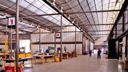 Interior de fábrica com trabalhadores em linha de produção