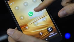 Mão segura celular abrindo o aplicativo WhatsApp