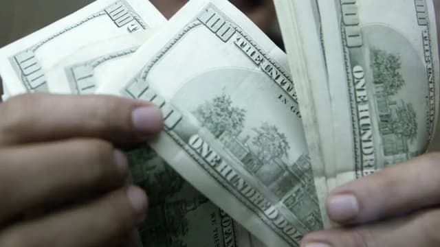 Mãos contando notas de dólar americano